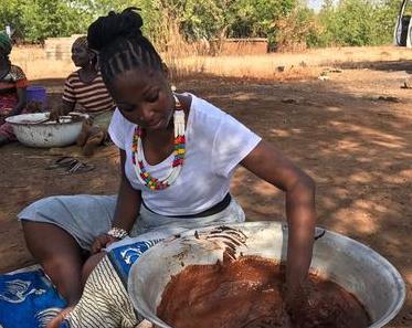 Woman kneading shea paste by hand to produce unrefined shea butter.